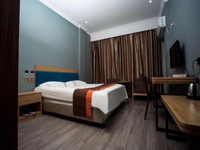 une chambre d'hôtel avec un lit et un bureau dans l'établissement JUN Hotels Jiangsu Wuxi Jiangyin Changjing Coach Station Store, à Wuxi