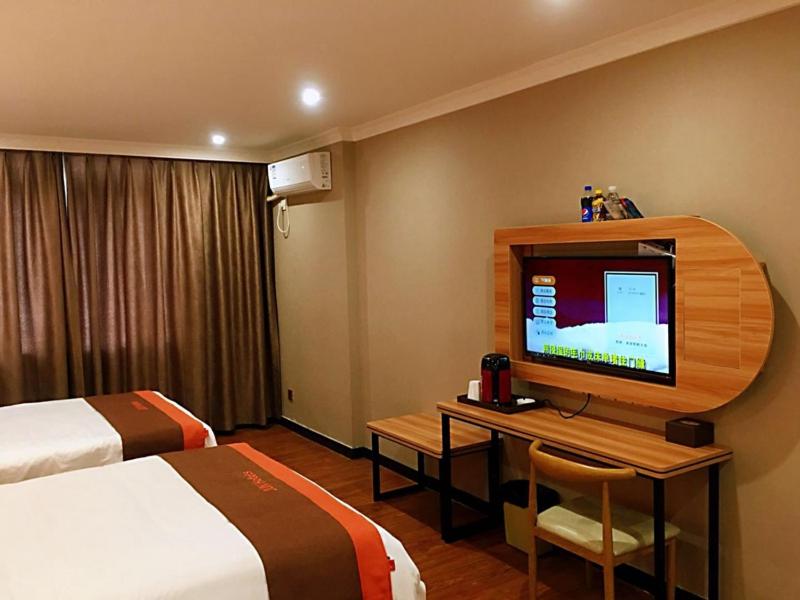 a hotel room with a bed and a desk with a television at JUN Hotels Chongqing Yubei District Jiangbei International Airport Airport Plaza in Yubei