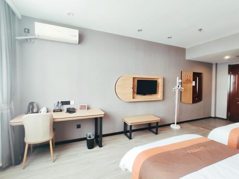 een hotelkamer met 2 bedden en een bureau bij JUN Hotels Inner Mongolia Tongliao Hexi Chuangye Avenue in Tongliao