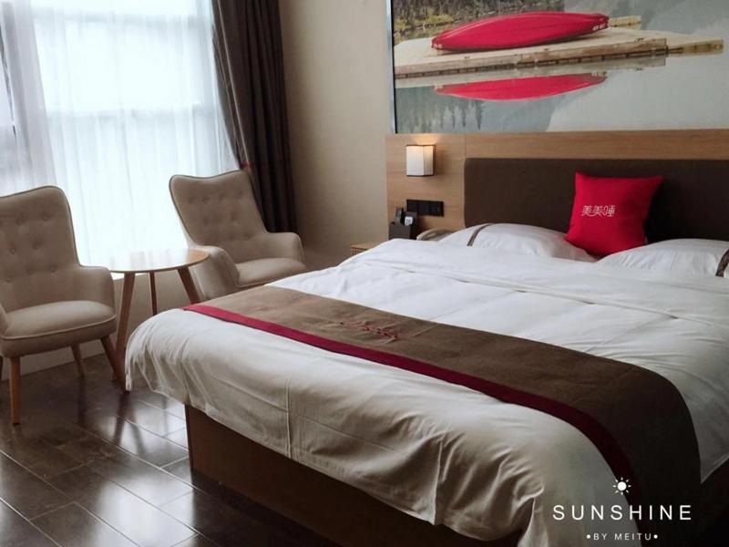 a bedroom with a large bed and a table and chairs at Thank Inn Chain Hotel Anhui Lu'an Shucheng Yuanda Ganghui in Lu'an