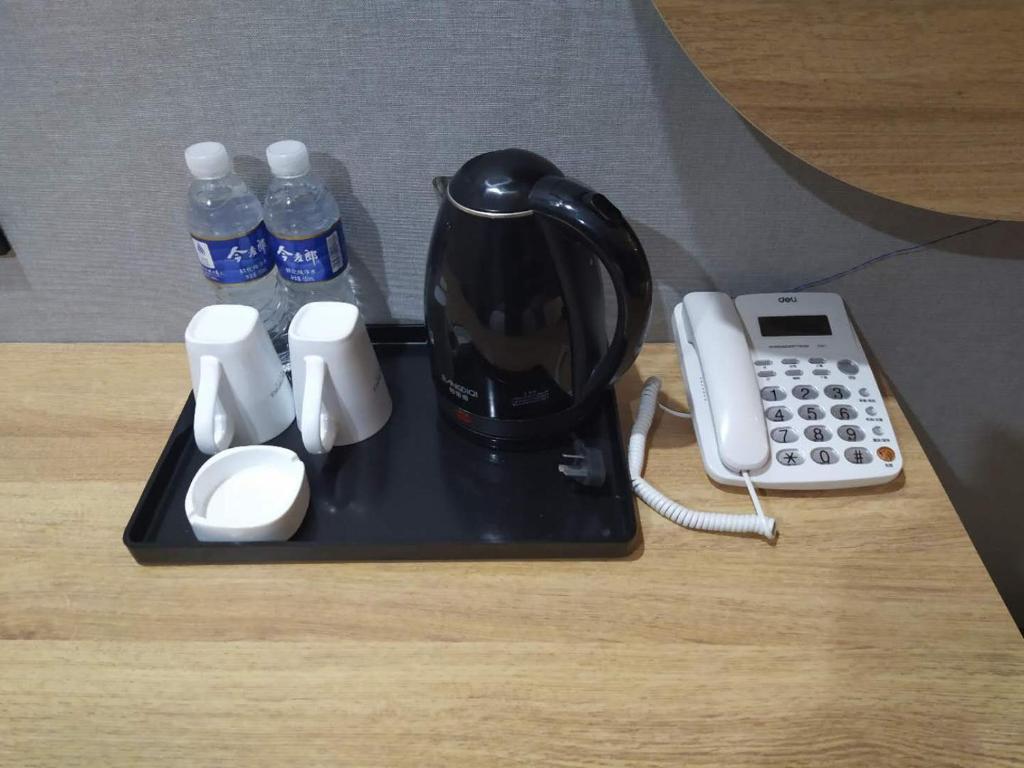 a tray with a coffee maker and a telephone and water bottles at JUN Hotels Suqian Muyang Baimeng Logistics Park in Suqian