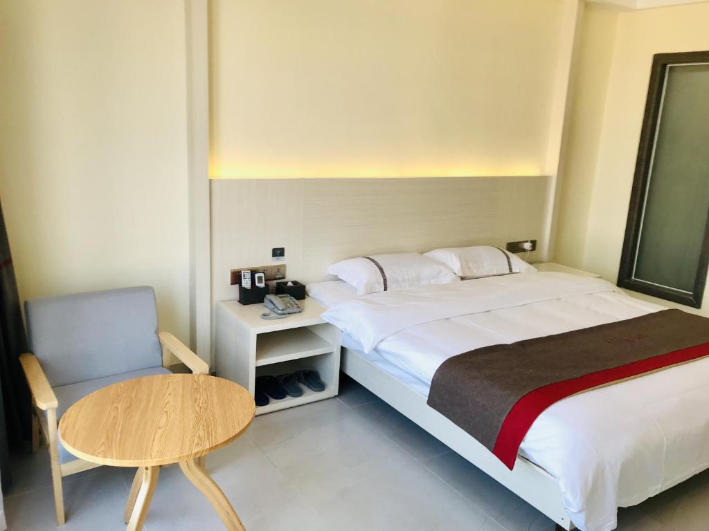 um quarto com uma cama, uma mesa e uma cadeira em Thank Inn Chain Hotel Hainan Oriental City Triangle Park em Dongfang