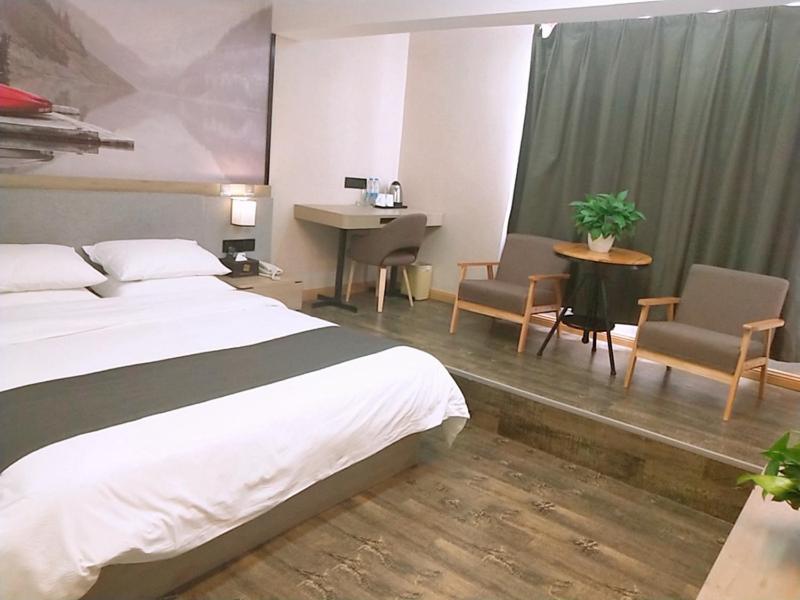 a hotel room with a bed and chairs and a desk at Thank Inn Plus Hotel Jiangsu Suzhou Taicang Liuhe Town Tinghai Road in Taicang