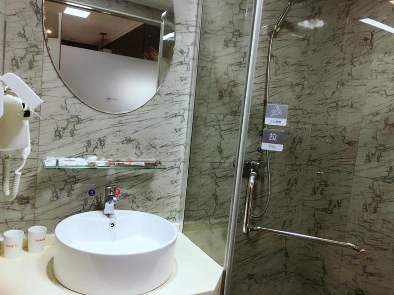 a bathroom with a sink and a shower with a mirror at Thank Inn Chain Hotel Hubei Yidu Chengxiang in Yidu