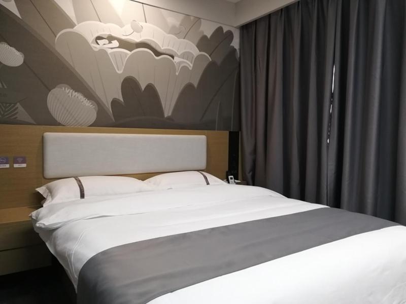 a bedroom with a white bed with a painting on the wall at Thank Inn Chain Hotel Yangzhou Hanjiang District Chahe University Town in Yangzhou