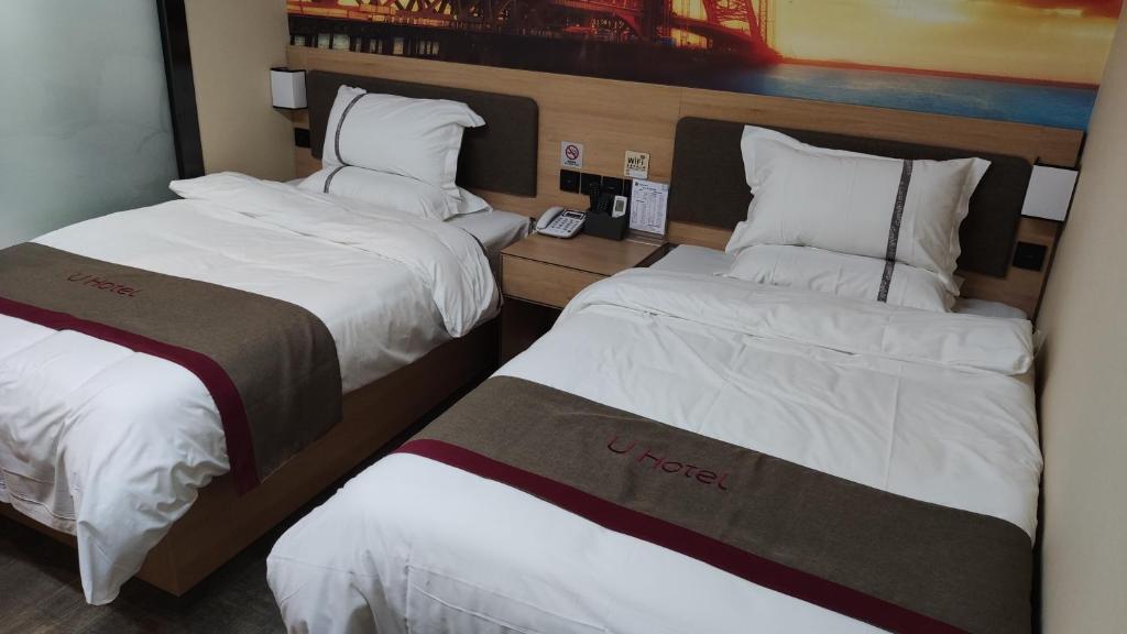 2 camas en una habitación de hotel con sábanas blancas en Thank Inn Chain Hotel Chengde Shuangluan District The Heyday Dynasty, en Chengde