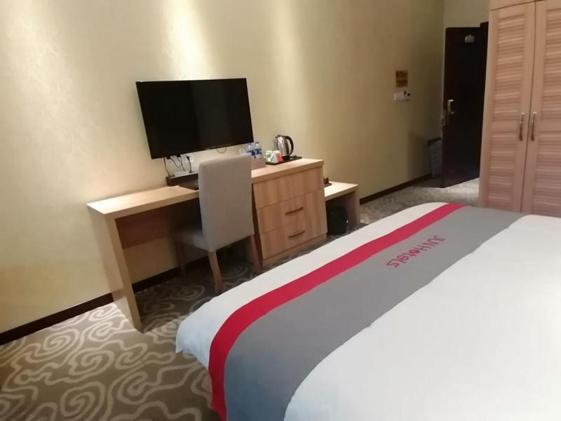 a hotel room with a bed and a desk with a television at JUN Hotels Sichuan Chengdu Jianyang Jiancheng Town Jianshe Road in Jianyang