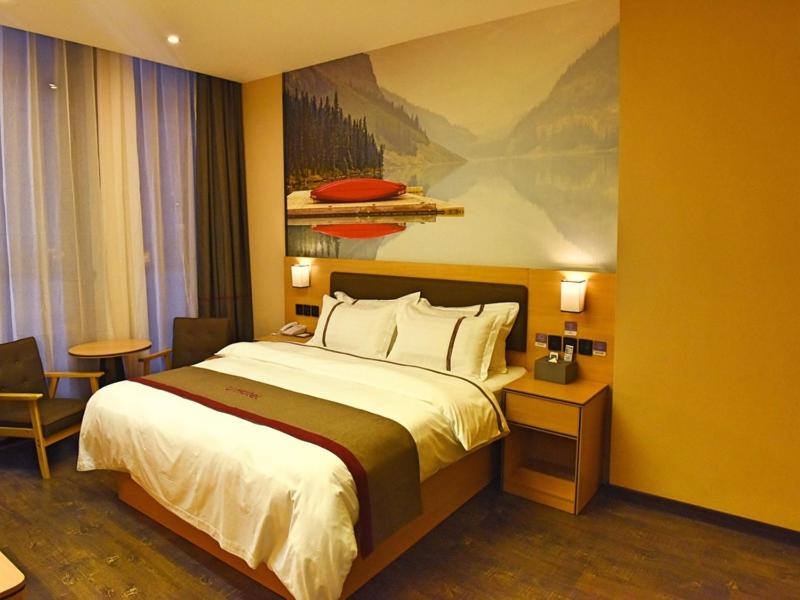 una camera d'albergo con un letto e un dipinto sul muro di Thank Inn Chain Hotel Huaihua Tongdao Bus Station a Tongdao