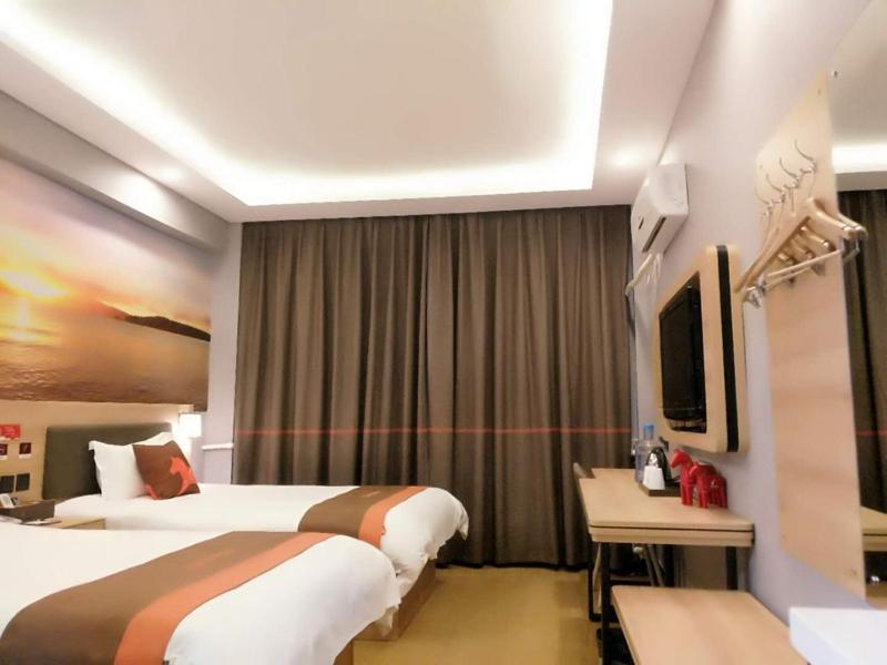 a hotel room with two beds and a desk and a tv at JUN Hotels Shandong Zaohuang Tengzhou Jinghe West Road in Tengzhou
