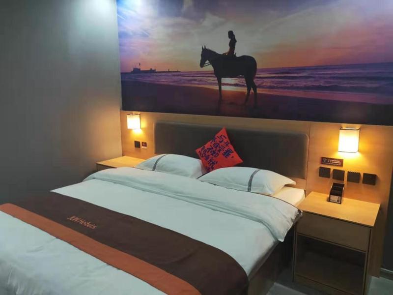 a bed with a picture of a person riding a horse at JUN Hotels Dezhou Decheng District Hubin South Avenue Wanda Plaza in Dezhou