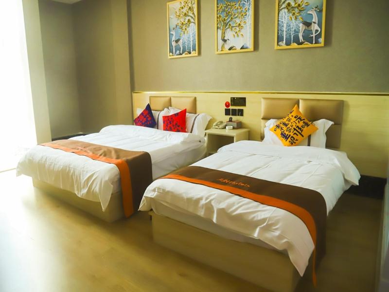 two beds sitting next to each other in a room at JUN Hotels Shandong Ji'nan Zhangqiu Diao Town Chemical Industrial Park 