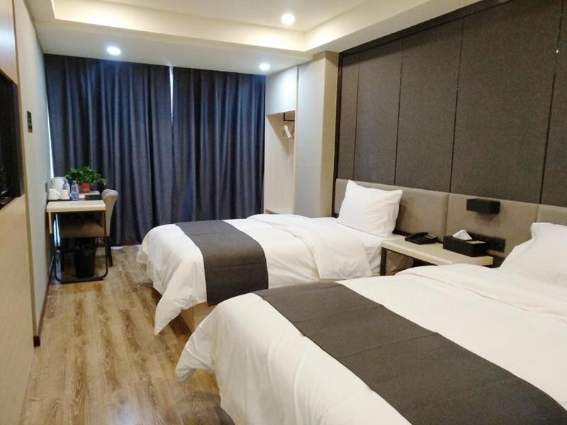 a hotel room with two beds and a desk at Thank Inn Plus Hotel Sichuan Guang'an Yuechi County Tianlong Street Store in Guang'an
