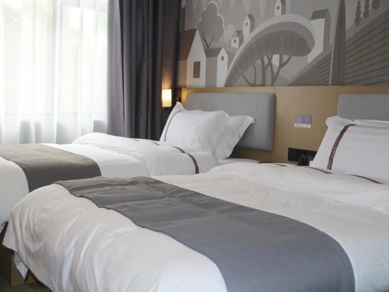 a row of white beds in a hotel room at Thank Inn Chain Hotel Jiangxi Ganzhou Quannan County Shoumei Road in Quannan