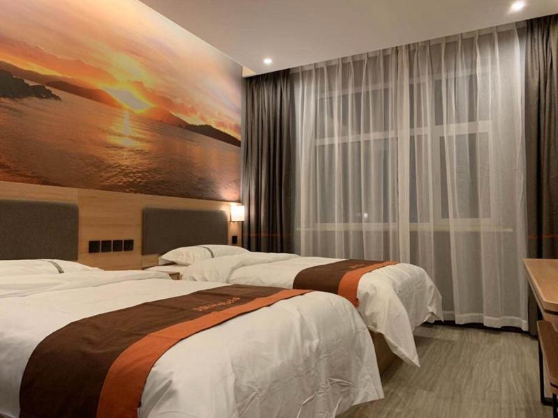 a hotel room with two beds and a painting on the wall at JUN Hotels Hebei Baoding Rongcheng Banzheng North Street Store in Baoding