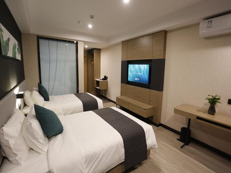a hotel room with two beds and a flat screen tv at Up and In Kashgar Xiyu Avenue Food Street in Kashgar