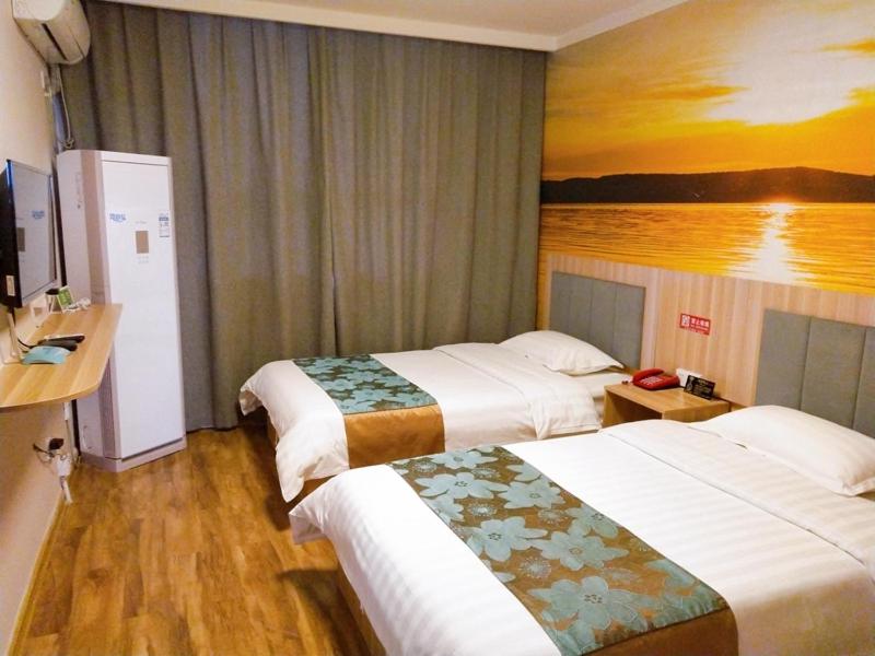 a hotel room with two beds and a painting on the wall at JUN Hotels Shandong Tai'an Daiyue District Tai'an High Speed Railway Station Store in Tai'an
