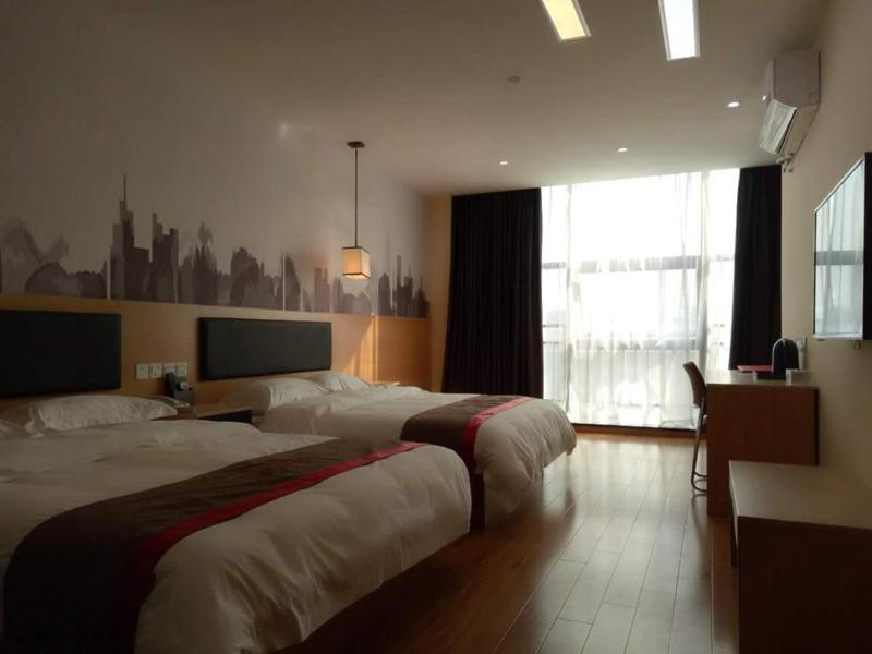 una camera d'albergo con due letti e una finestra di Thank Inn Chain Hotel Chizhou Zhanqian District Railway Station a Chizhou
