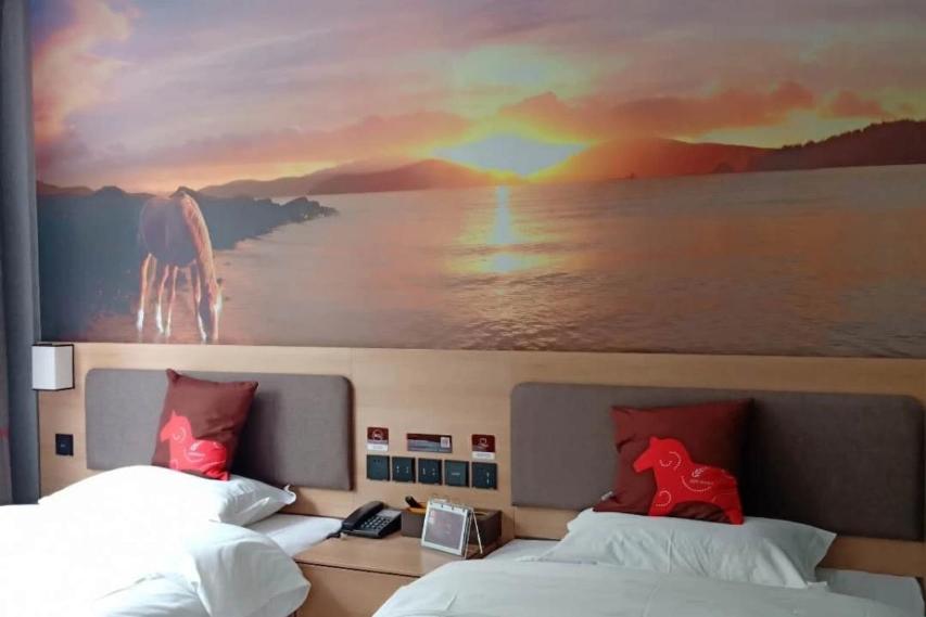 a painting above two beds in a hotel room at JUN Hotels Hebei Hengshui Renmin Road 13 Middle School in Hengshui