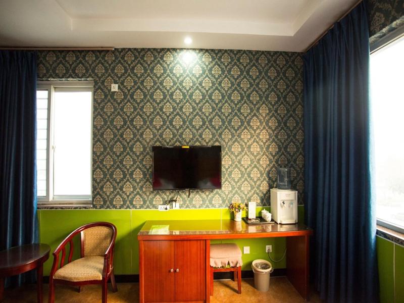 a room with a table and a tv on the wall at JUN Hotels He'nan Anyang Huaqiang Xintiandi in Anyang