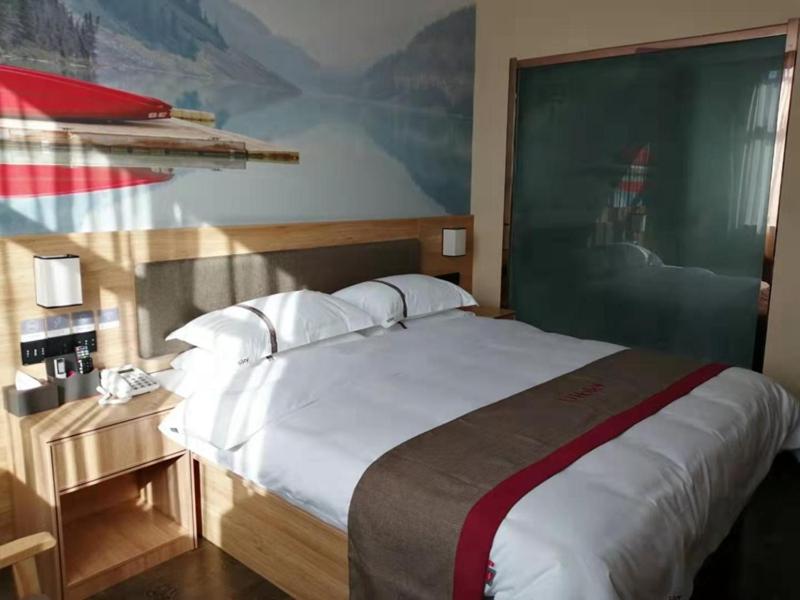a bedroom with a large bed and a large painting on the wall at Thank Inn Chain Hotel Anhui Suzhou Lingbi County Qimeishan Road Store in Suzhou