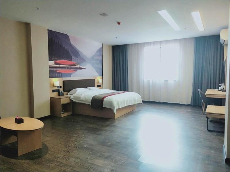 a bedroom with a bed and a large window at Thank Inn Chain Hotel Jiangmen Kaiping Shuikou Passenger Transport Station in Jiangmen