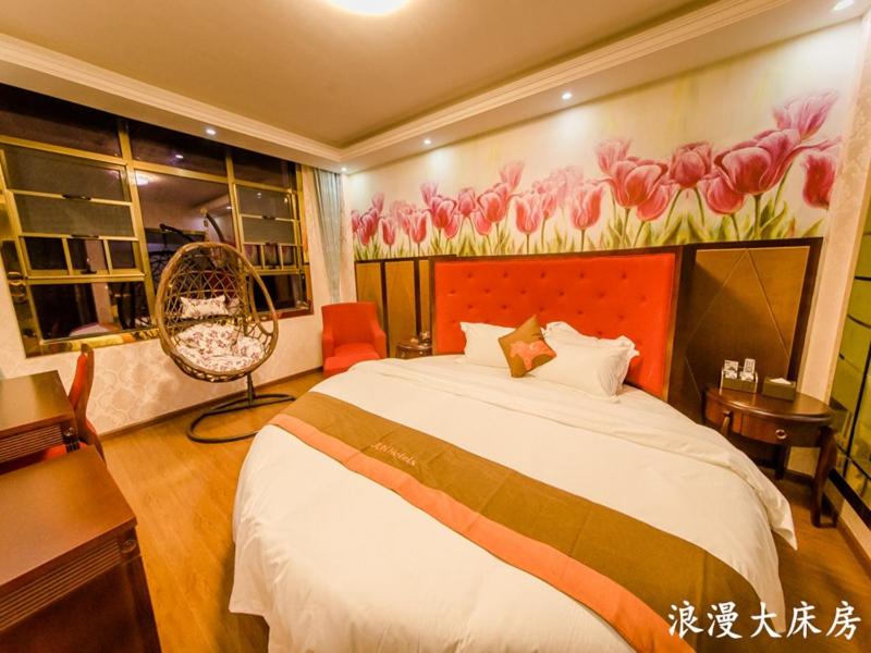 1 dormitorio con 1 cama grande con una pintura floral en la pared en JUN Hotels Hunan Changsha Huannghua Airport, en Changsha
