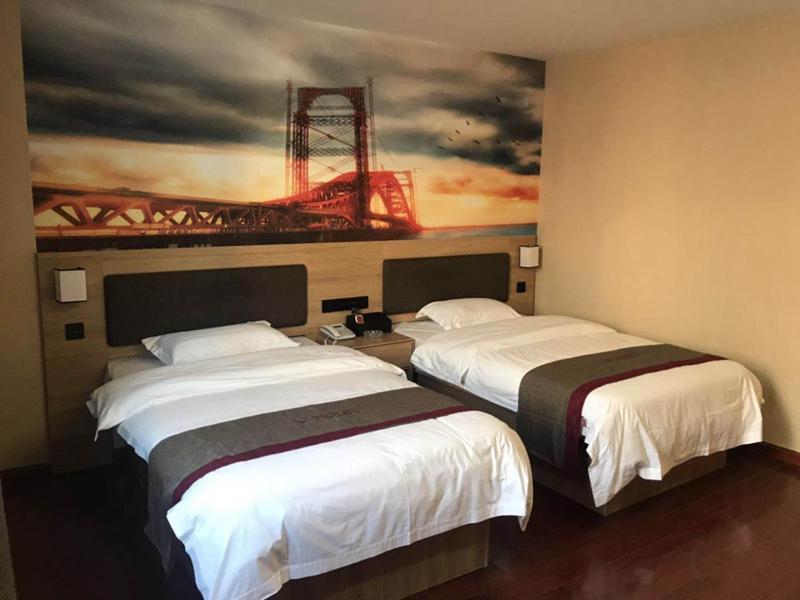 two beds in a hotel room with a painting on the wall at Thank Inn Chain Hotel Jiangsu Nanjing Jiangning Taowu in Nanjing