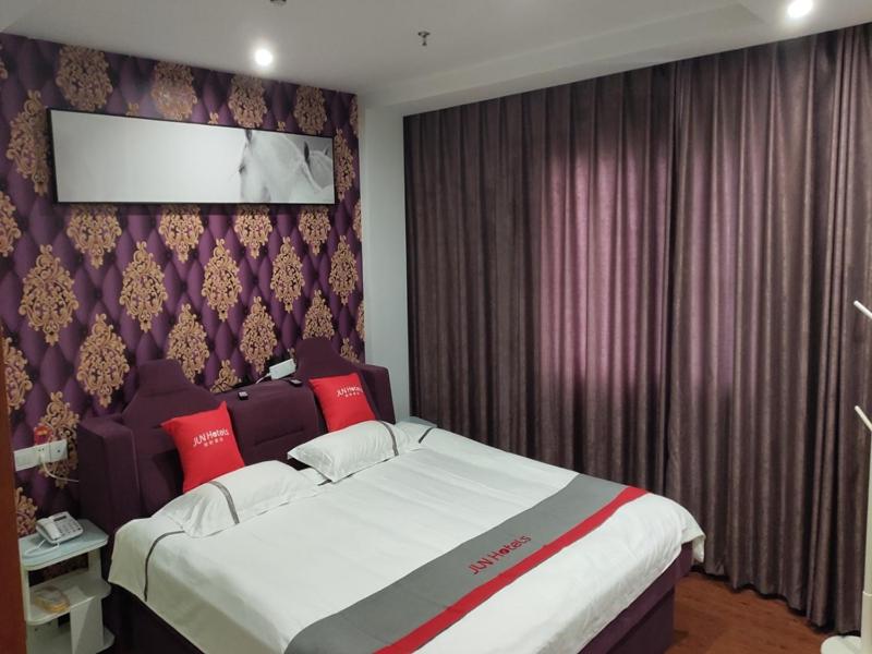ein Schlafzimmer mit einem großen Bett mit roten Kissen in der Unterkunft JUN Hotels Shanghai Chongming Xuegong Road Meizhou Road in Shanghai
