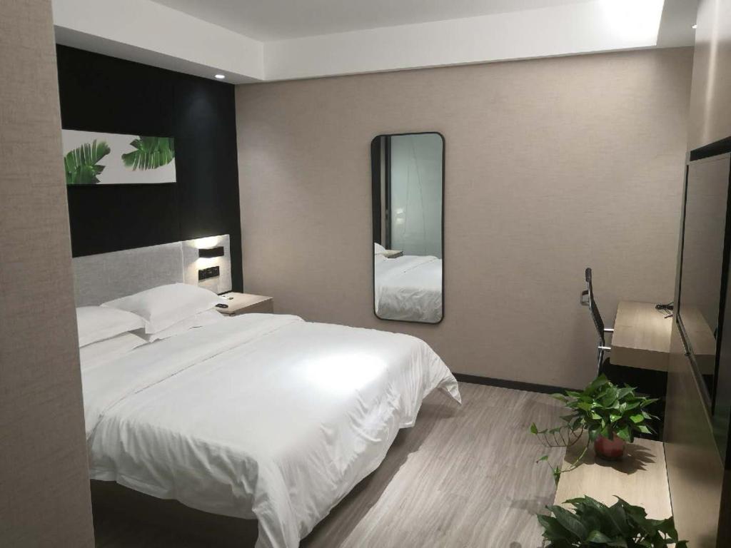 1 dormitorio con 1 cama blanca grande y espejo en Thank Inn Chain Hotel Heze Mudan District China Peony Garden, en Heze