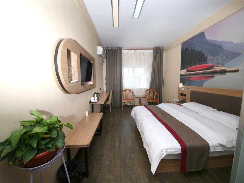 a hotel room with a large bed and a table at Thank Inn Chain Hotel Shandong Dezhou Lingcheng District Lingzhou Road Ginza in Dezhou