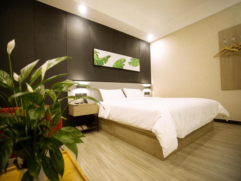Un dormitorio con una gran cama blanca y una planta en Up And In Baotou Qingshan District Central International en Baotou
