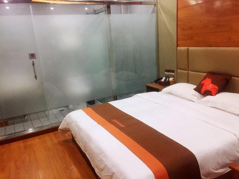 a bedroom with a large bed with a glass wall at JUN Hotels Jiangsu Taizhou Taixing Zhongnan Central City in Taixing