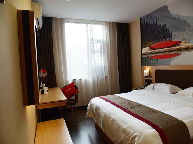 a hotel room with a bed and a desk and a window at Thank Inn Chain Hotel Guizhou Tongren Bijiang District High-speed Railway Station Qingshui Avenue Store in Tongren