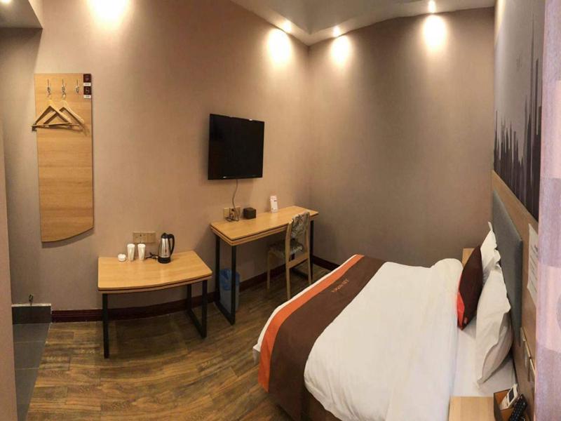 1 dormitorio con 1 cama, escritorio y TV en JUN Hotels Hunan Zhuzhou Shifeng District Qingshi Plaza en Zhuzhou
