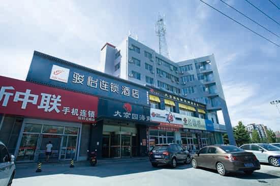un edificio con coches estacionados en un estacionamiento en JUN Hotels Shandong Weihai Huancui District High Speed Rail North Station Store, en Weihai