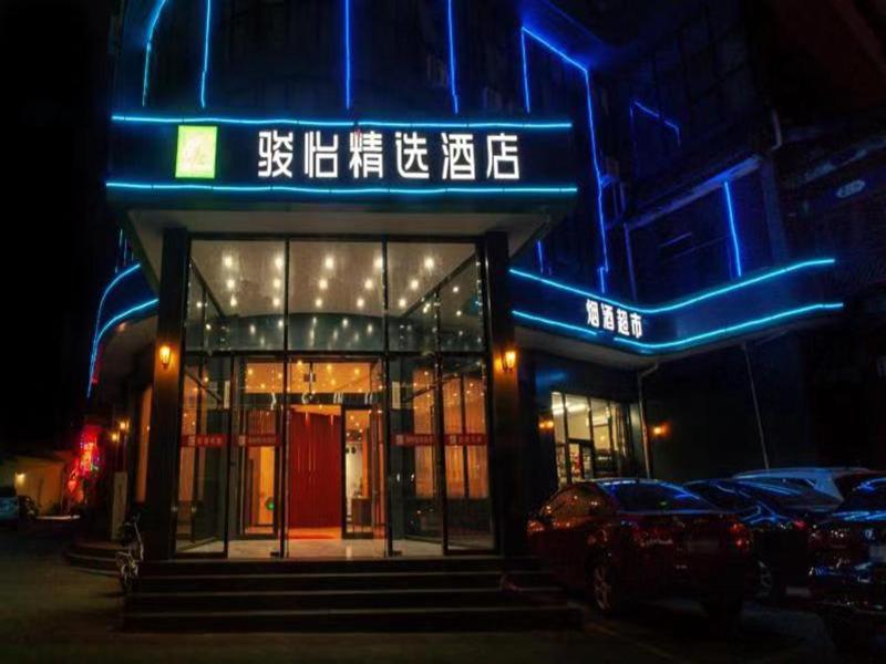 un edificio con una señal de neón azul delante de él en JUN Hotels Langfang Guangyang District Wanda Plaza, en Langfang