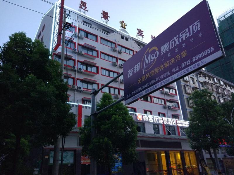 een groot gebouw met een bord ervoor bij Thank Inn Chain Hotel Xiaogan Hanchuan West Lake Avenue in Xiaogan