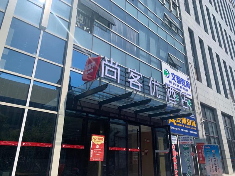 a building with a sign on the front of it at Thank Inn Chain Hotel Yancheng Tinghu District Changting Commercial building in Yancheng