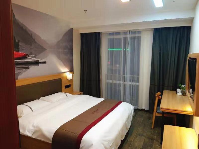 een slaapkamer met een bed, een bureau en een raam bij Thank Inn Chain Hotel Jiangsu Suzhou Changshu Haiyu Town in Changshu