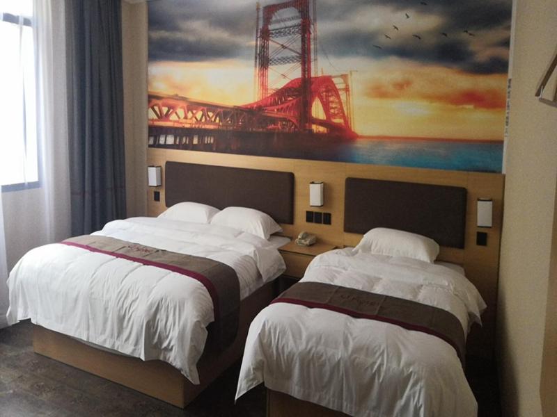 two beds in a hotel room with a painting on the wall at Thank Inn Chain Hotel Guizhou Tongren Jiangkou County Fengjingshan Park Fenghuang Road Store in Tongren