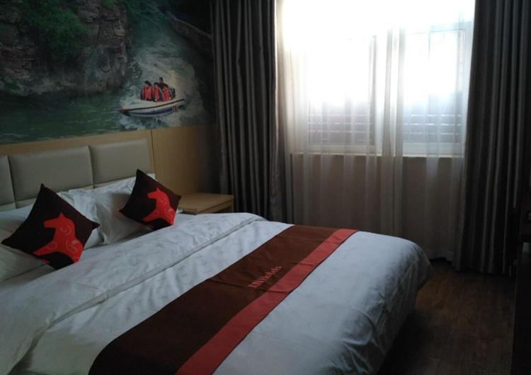 una camera da letto con letto, cuscini e finestra di JUN Hotels Anyang Beiguan District Railway Station ad Anyang