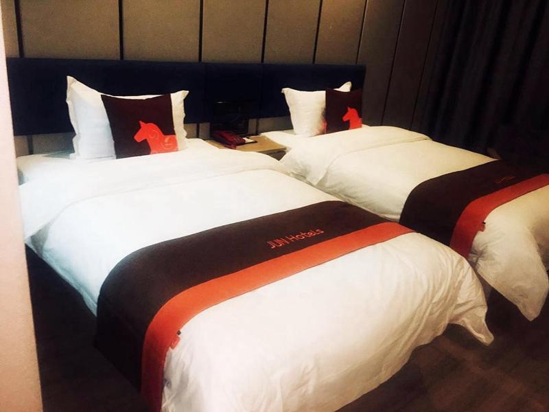 a hotel room with three beds with red crosses on them at JUN Hotels Qinghai Xining Chengdong District Xinqian International Plaza Store in Xining