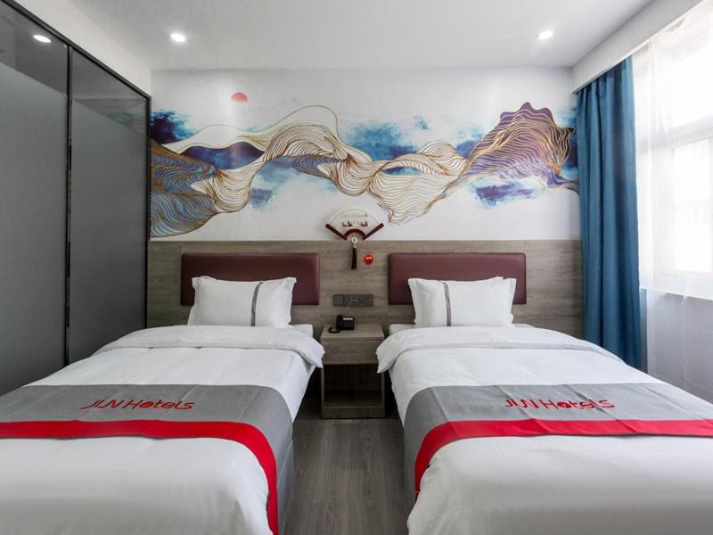duas camas num quarto com um quadro na parede em JUN Hotels Shanxi Taiyuan Yingze District Chaoyang Street Store em Taiyuan