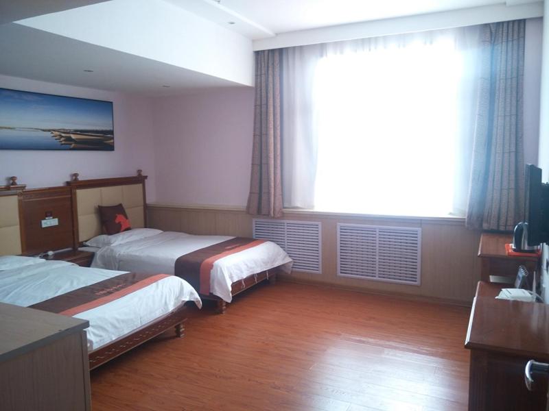 a hotel room with two beds and a window at JUN Hotels Yulin Yuyang District South Gate Bus Station in Yulin