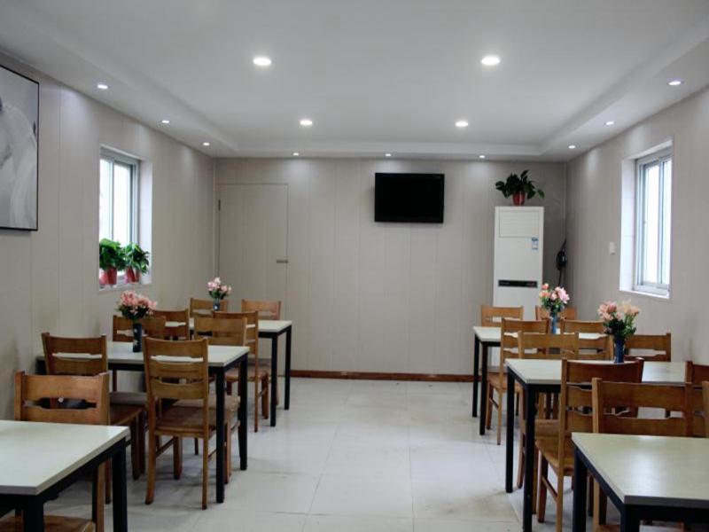 uma sala de jantar com mesas e cadeiras e uma televisão em JUN Hotels He'nan Zhoukou Shenqiu Zhaofeng Avenue em Zhoukou