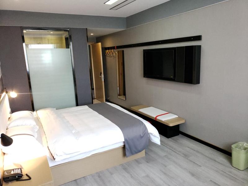 um quarto com uma cama e uma televisão de ecrã plano em Thank Inn Chain Hotel Anhui Anqing Yixiu District Government University Town em Anqing