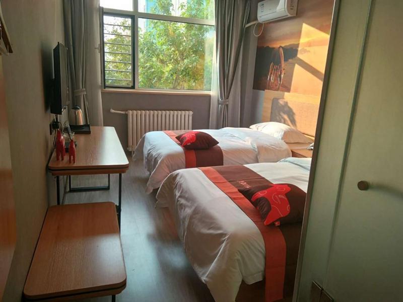a room with two beds and a table and a window at JUN Hotels Hebei Hengshui Taocheng Railway Station Square West Side in Hengshui