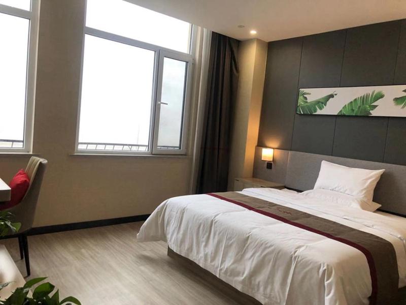 a bedroom with a large bed and two windows at Thank Inn Chain Hotel Liaocheng Yanggu County Fucheng in Liaocheng