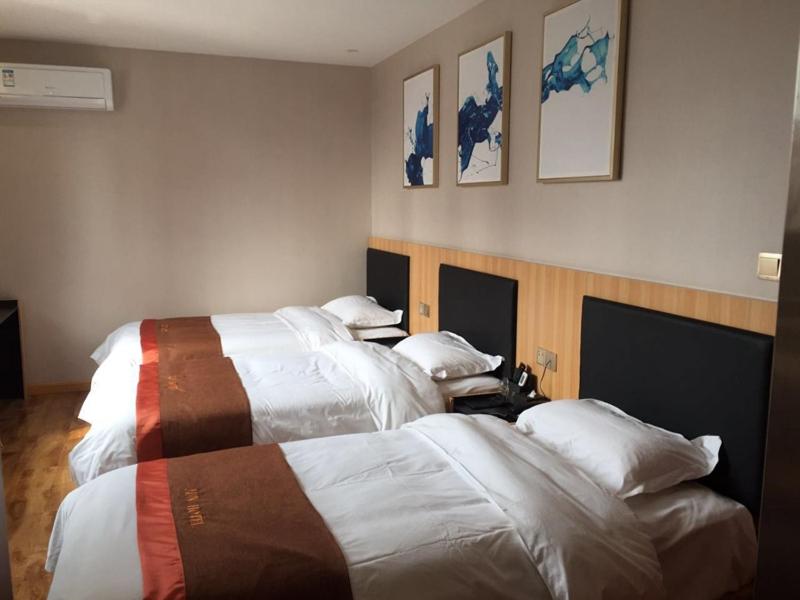 ein Hotelzimmer mit 2 Betten und 2 Bildern an der Wand in der Unterkunft JUN Hotels Henan Luoyang Xigong District Central Bus Station in Luoyang
