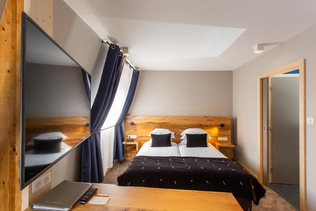 a bedroom with a bed and a desk with a television at Hôtel Le Rapp in Colmar